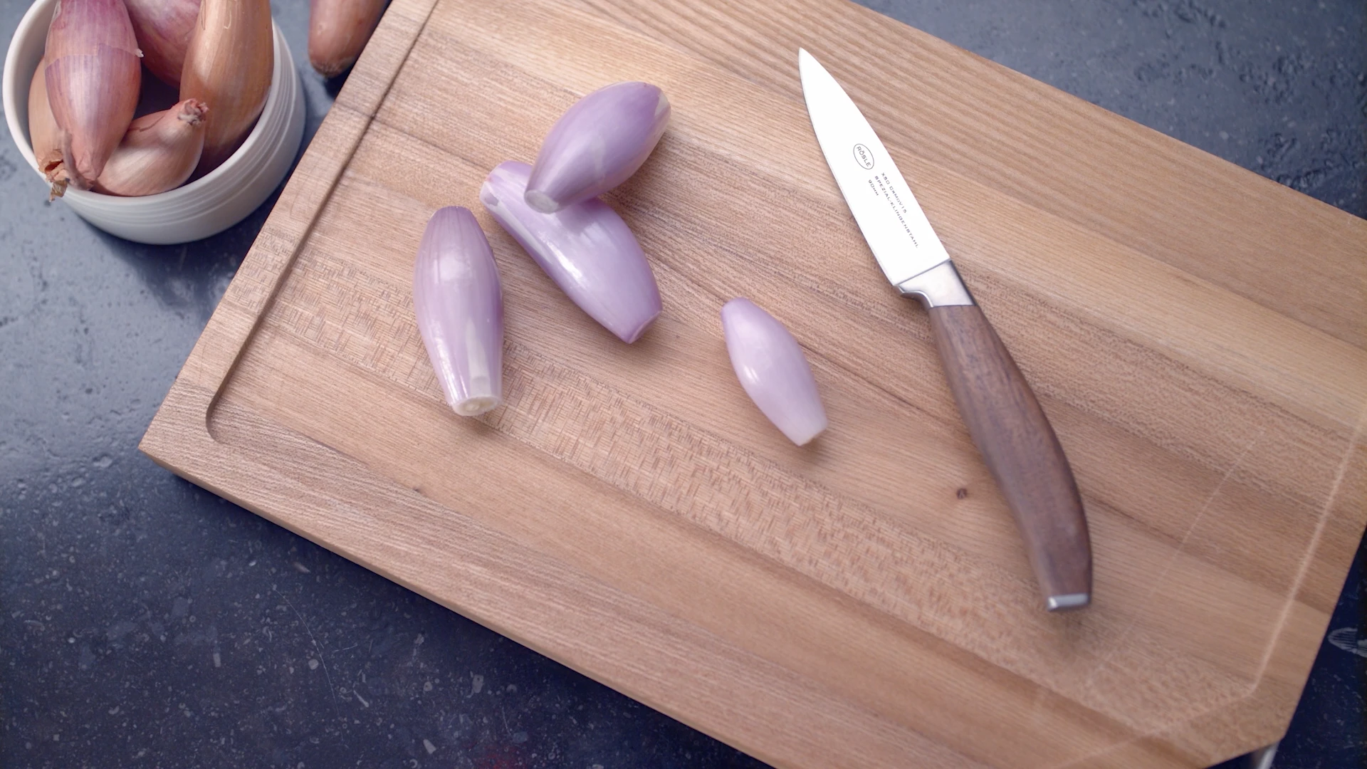 Holzschneidebrett mit geschnittenen Schalotten und Messer auf Küchenarbeitsplatte, produziert von Bürobewegt.