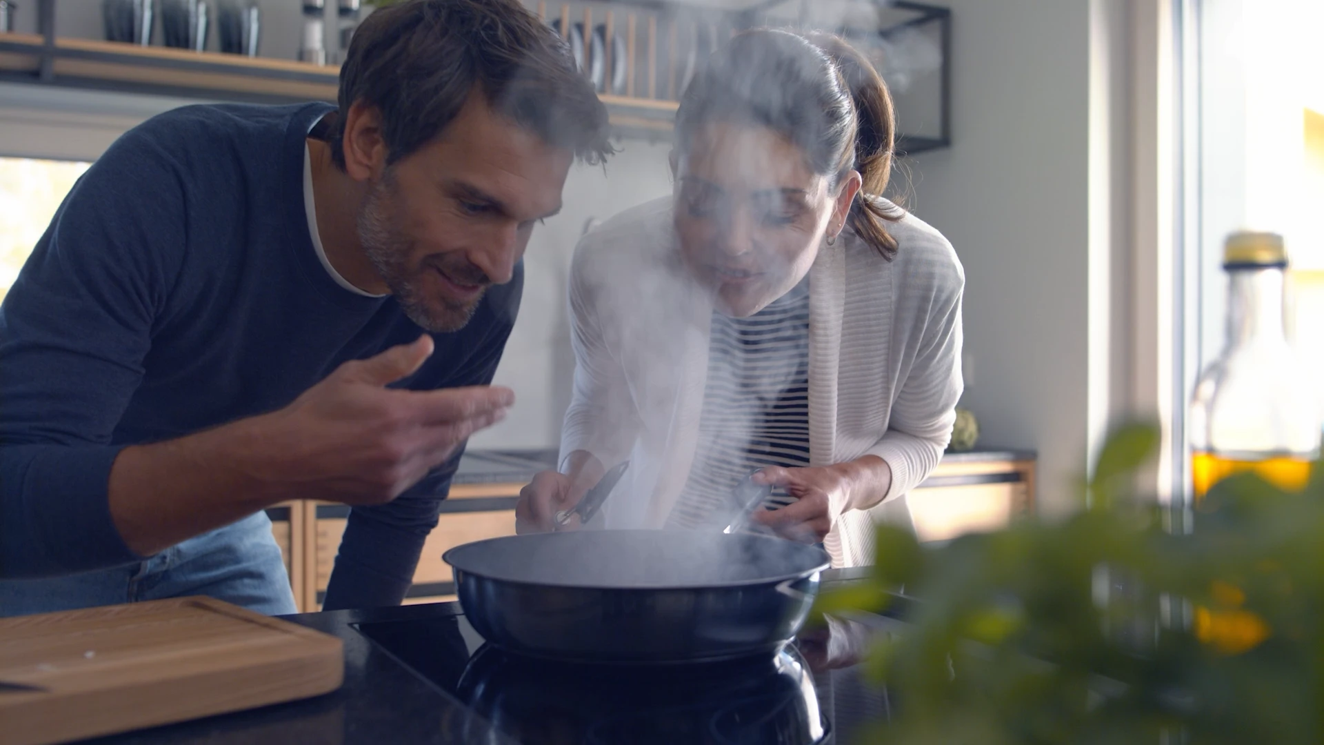 Ein Mann und eine Frau kücheln zusammen und inspizieren neugierig den dampfenden Inhalt einer Pfanne.