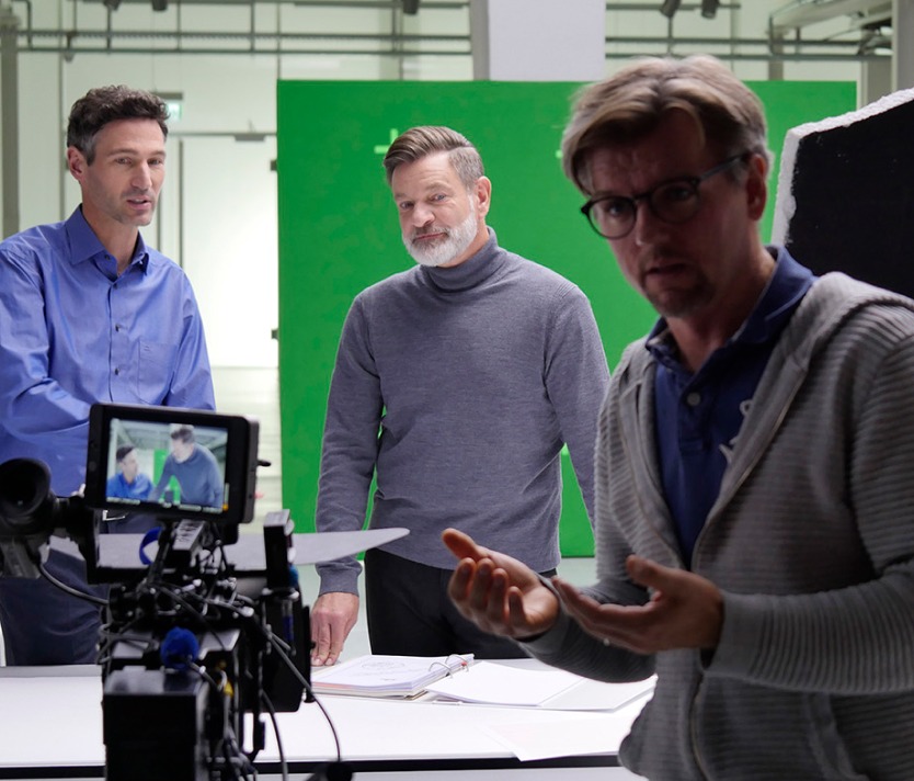 Drei Männer bei der Videoproduktion im Studio, Einsatz von Greenscreen-Technologie.