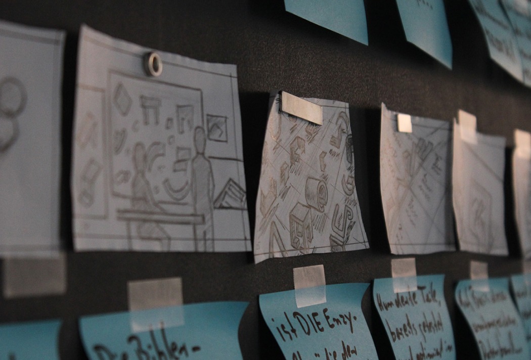 Handgezeichnete Skizzen auf blauen Haftnotizen an einer Wandtafel, Detailansicht.