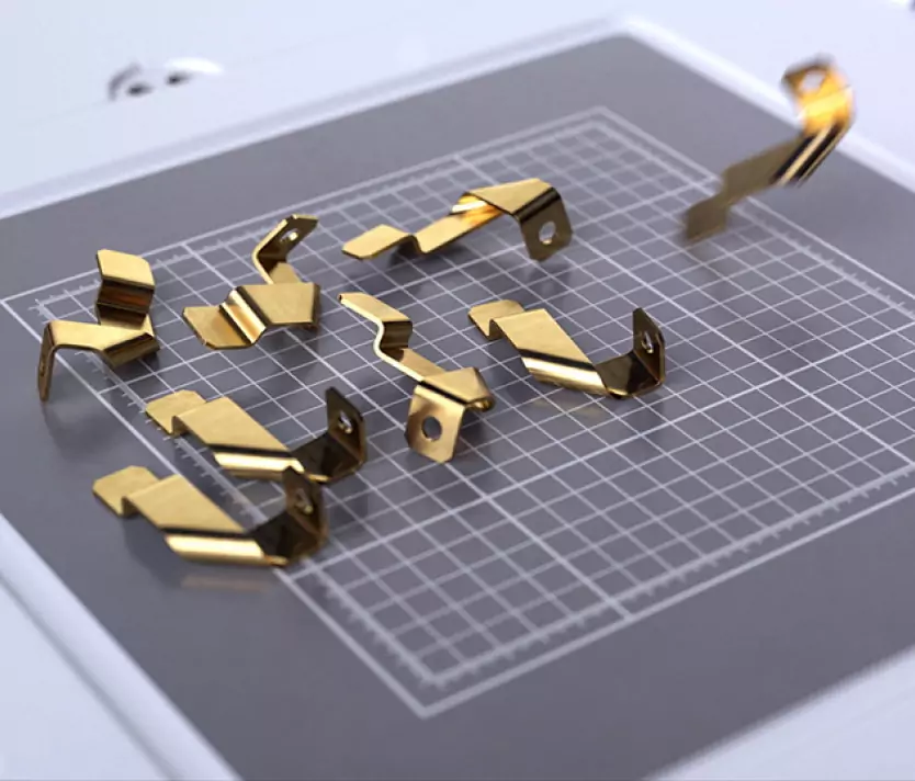 Goldplattierte Metallclips auf einem karierten Schneideuntergrund. Ideal für Konstruktionen und Befestigungen.