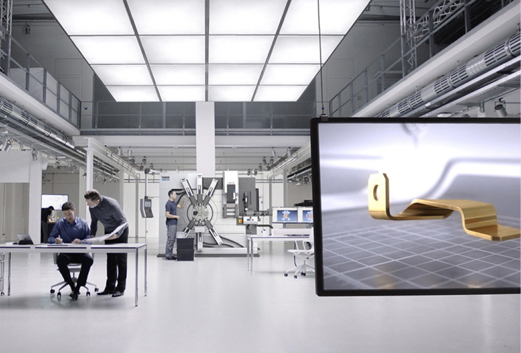 Hightech-Fabrik mit Ingenieuren bei der Arbeit. Moderne Maschinen und CAD-Entwurf auf Bildschirm im Vordergrund.