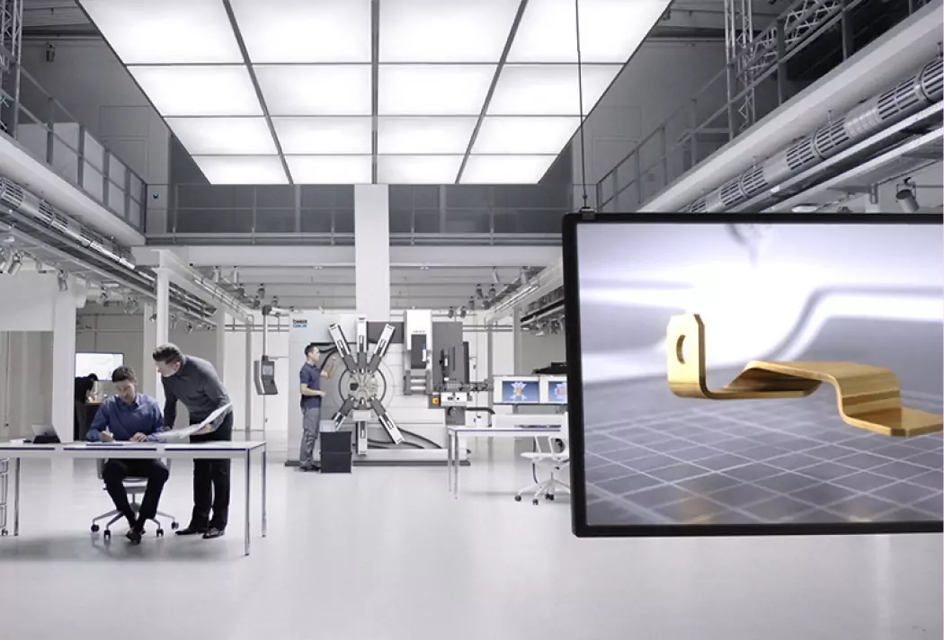 Hightech-Fabrik mit Ingenieuren bei der Arbeit. Moderne Maschinen und CAD-Entwurf auf Bildschirm im Vordergrund.