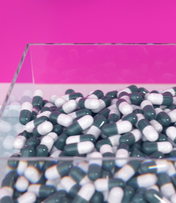Grüne und weiße Kapseln in einem Glasbehälter vor einem pinkfarbenen Hintergrund.