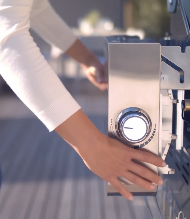 Person bedient modernen Grillregler im Freien. Nahaufnahme von Edelstahlgrill mit Hand.