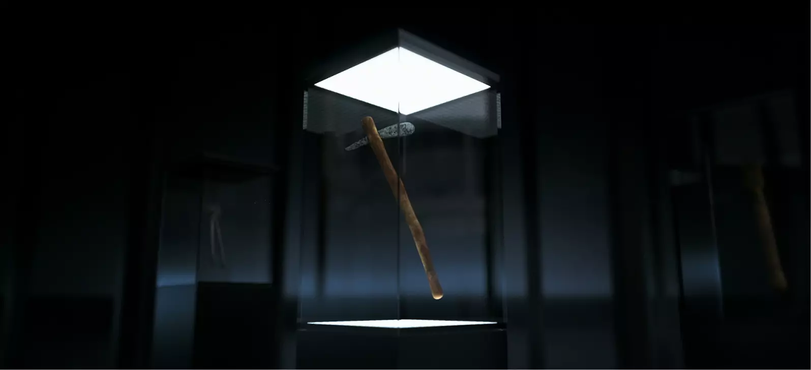 Altes Steinwerkzeug, präsentiert in beleuchtetem Glaskasten im Museum, dunkler Hintergrund.