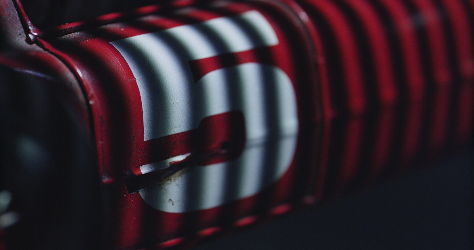 Rote Metallstruktur mit gestreifter Nummer 5, die Licht- und Schattenmuster zeigt.